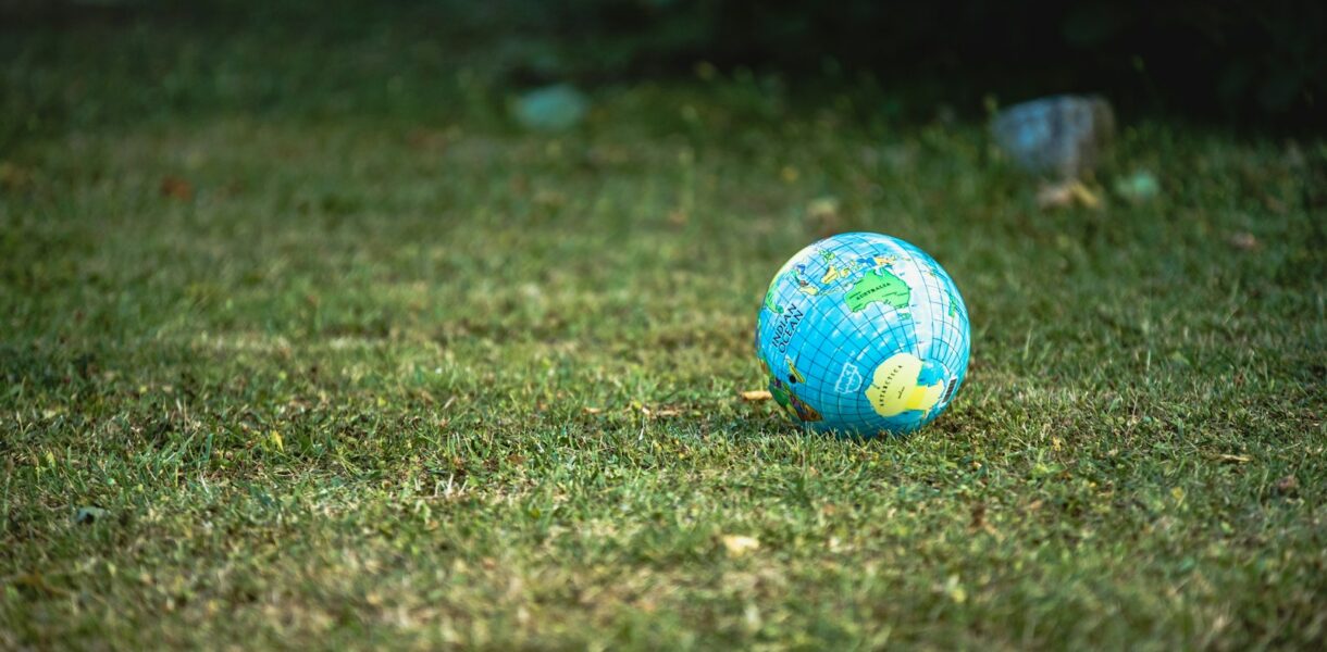 blue and white desk globe on green grass field during daytime