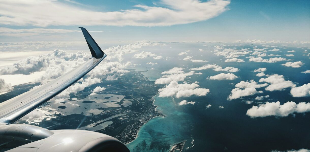 photo of airplane wing under blue sky at daytime