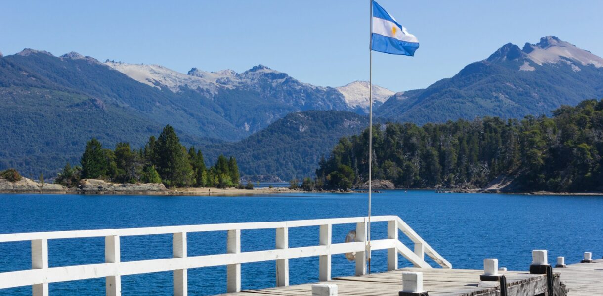 white and blue flag on wooden dock near body of water during daytime