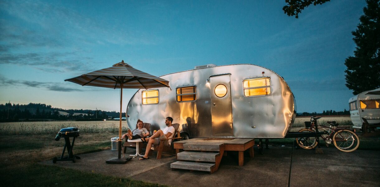 man and woman sitting in front of RV trailer