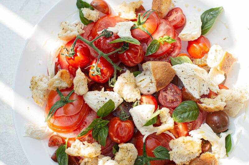 sliced tomato and green leaf vegetable on white ceramic plate