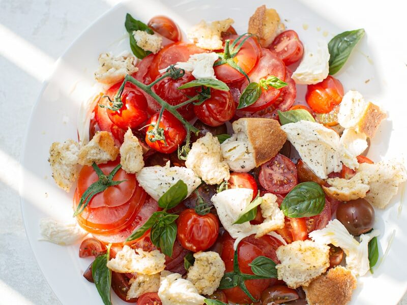 sliced tomato and green leaf vegetable on white ceramic plate