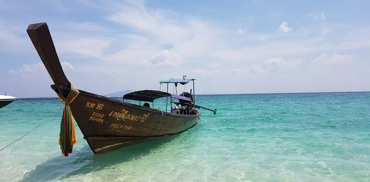 brown and white boat on sea under blue sky during daytime