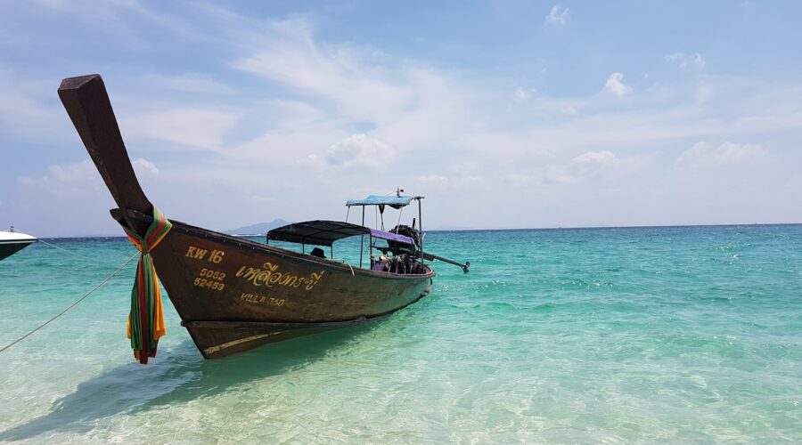 brown and white boat on sea under blue sky during daytime
